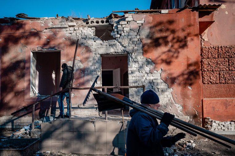 Mensen ruimen puin na een Russische raketaanval op een ziekenhuis in Cherson. Beeld AFP