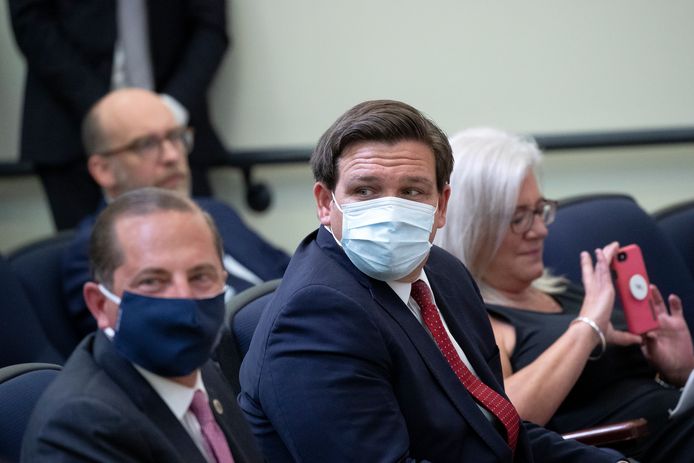Governeu Ron DeSantis van Florida (midden) met mondkapje op. Het is niet verplicht in de staat een mondkapje te dragen.
