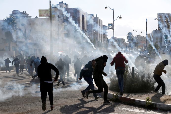 Palestijnse demonstranten rennen weg van het traangas dat de Israëlische troepen afvuren tijdens een protestactie tegen het besluit van Trump om Jeruzalem te erkennen als ISraëls hoofdstad.