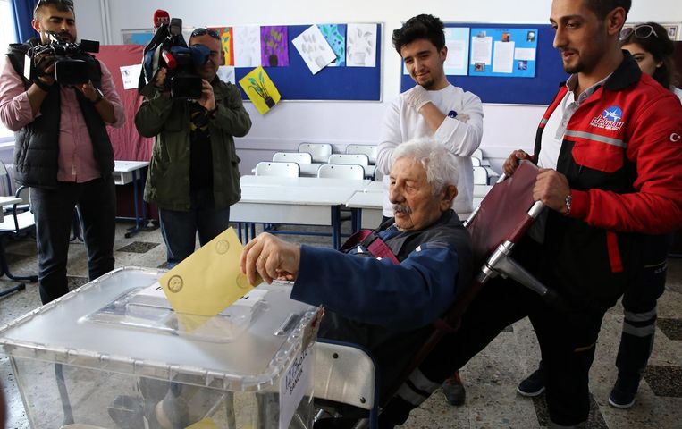 Verzorgers helpen een oudere meneer in een rolstoel bij het uitbrengen van zijn stem, Ankara, 16 april. Beeld getty