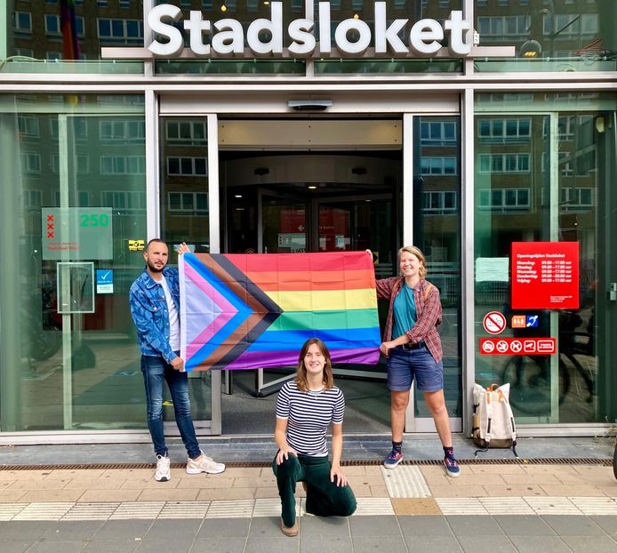 Initiatiefnemer Tirza Gevers, Queer Club West-lid Ilias Zian en flatbewoner Julia Zegerling nemen de eerste vlag in ontvangst.