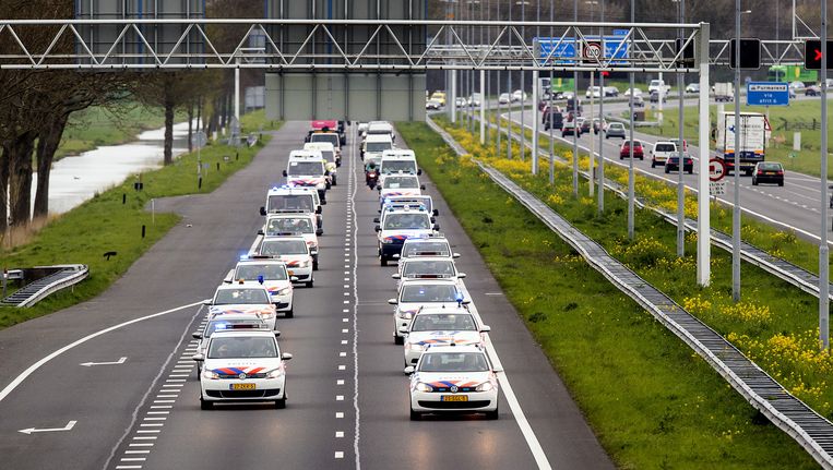 Een stoet politieauto's rijdt op de A7 met een gangetje van 60 kilometer per uur. Beeld anp