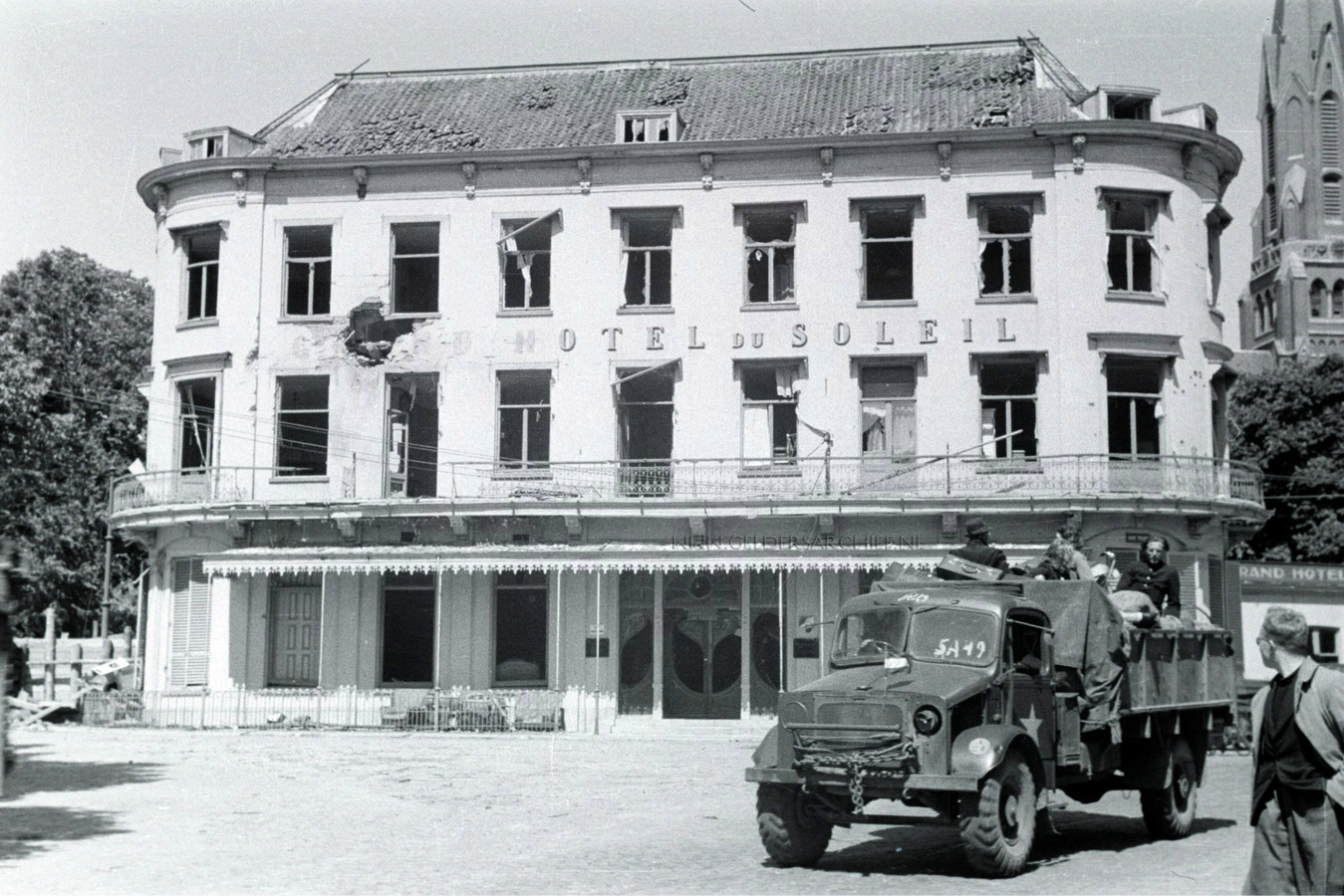 Grand Hotel Du Soleil in 1945. Een voltreffer heeft het woord ‘Grand’ van de gevel geblazen. Op de geallieerde vrachtwagen terugkerende evacués.