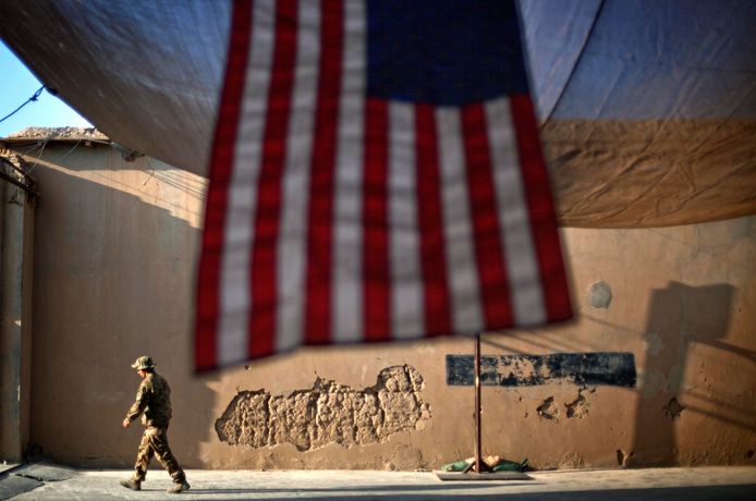 Archiefbeeld. Een Amerikaanse soldaat loopt voorbij een Amerikaanse vlag in Afghanistan.