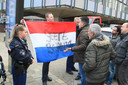 Een man met Nederlandse vlag met de tekst 'Geert bedankt' laat buiten het politiebureau een tegengeluid horen.