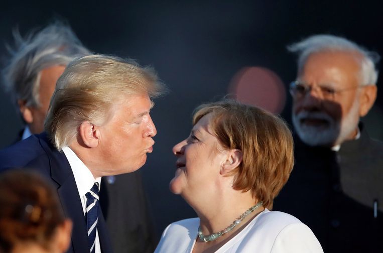 President Donald Trump poogt Angela Merkel te zoenen tijdens de fotosessie op de G7-top in Biarritz.  Beeld AP