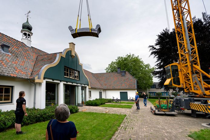 De 2.200 kilo zware betonnen bank zweeft boven het dak van De Voorste Venne. Kraanmachinist Maurice van Geel 'stuurt'.