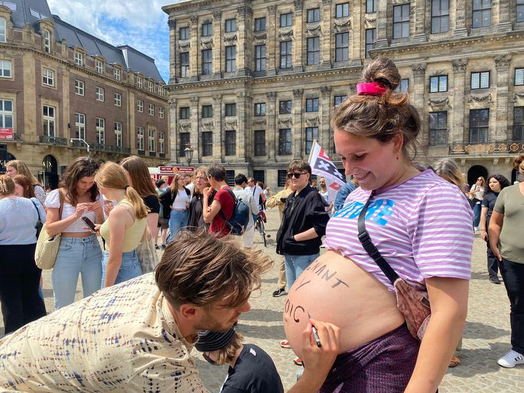 Joris Pals (37) schrijft met een markeerstift 'pregnant by choice' op de buik van zijn hoogzwangere vriendin Cathrien Maas (33). Beeld Malika Sevil