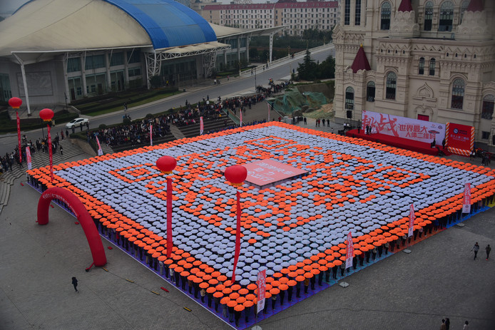 Ruim Chinese 2500 studenten vormen met paraplu's de grootste menselijke QR-code ter wereld bij de Sias University of Zhengzhou. Foto VCG