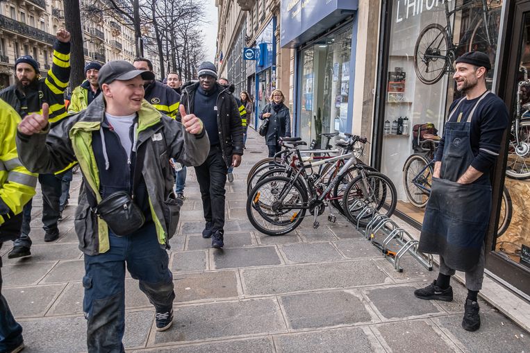 Fietsenmaker/verkoper Kevin Olanier kijkt toe hoe Gele Hesjes langs zijn fietsenwinkel gaan.  Beeld Joris Van Gennip