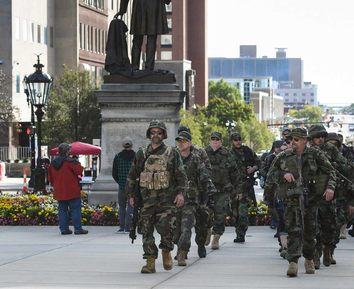 Leden van de Michigan Home Guard militie marcheren naar het parlementsgebouw van hun staat Michigan hun steun te betuigen aan het recht op wapenbezit.  Ze protesteerden ook tegen maatregelen om corona in te dammen.  Beeld AP