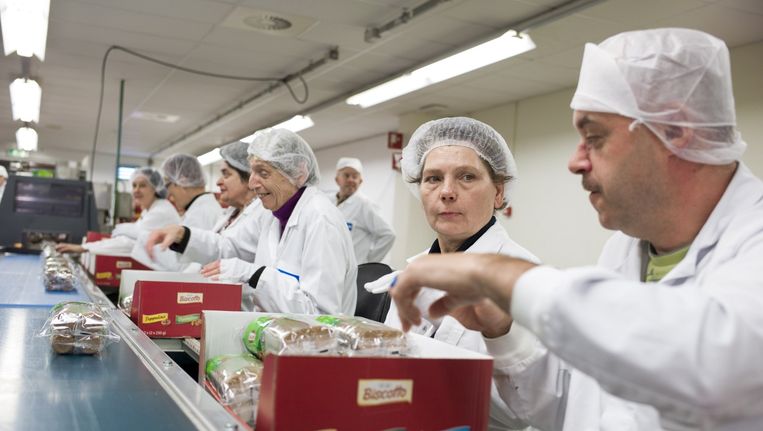 Medewerkers aan de lopende band bij sociale werkplaats Licom in Kerkrade. Beeld Chris Keulen