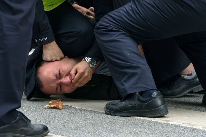 Gli agenti di polizia arrestano un manifestante durante una manifestazione a Shanghai.