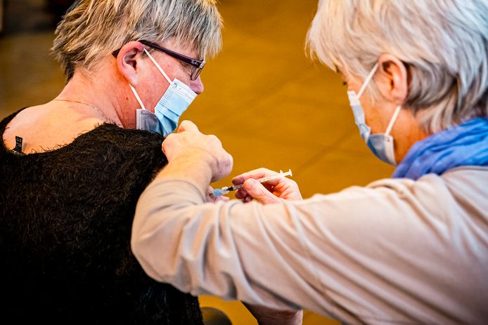 Een vrouw krijgt een coronavaccinatie in de Koepelhal in Tilburg. De GGD is daar gestart met een vrije inloop voor mensen die een boosterprik willen halen.