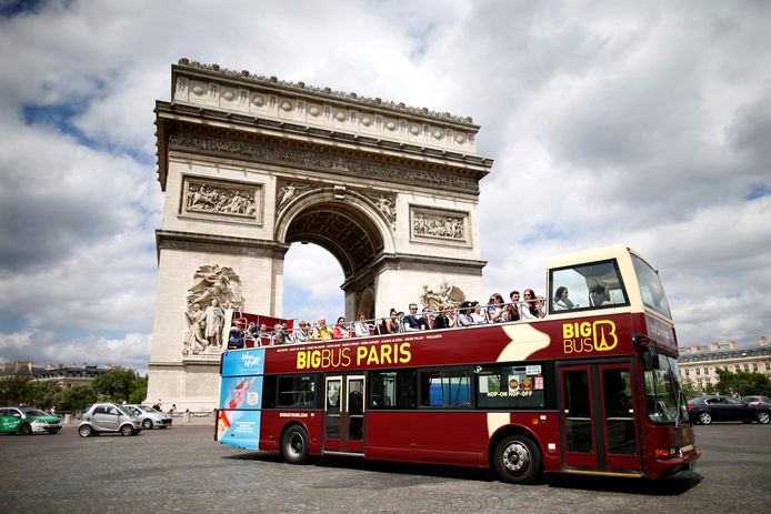 Toeristen maken een ritje langs de Arc de Triomphe in een dubbeldekkerbus.