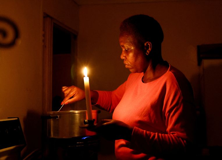 Een inwoner van Soweto kookt noodgedwongen bij kaarslicht vanwege een stroomonderbreking bij energiebedrijf Eskom in Zuid-Afrika. Beeld Reuters