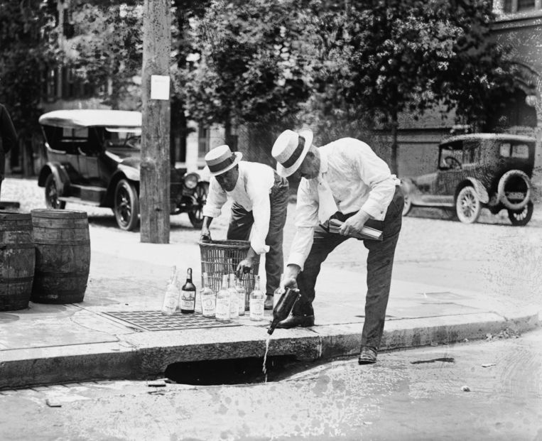 Agenten gooien drank de afvoer in, VS, ca. 1921. Beeld Getty