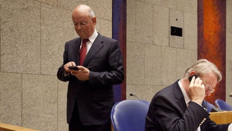 Ministers Hans Hillen en Uri Rosenthal telefoneren tijdens een korte pauze in de Tweede Kamer tijdens het debat over de Nederlandse bijdrage aan de missie in Libië. Beeld anp