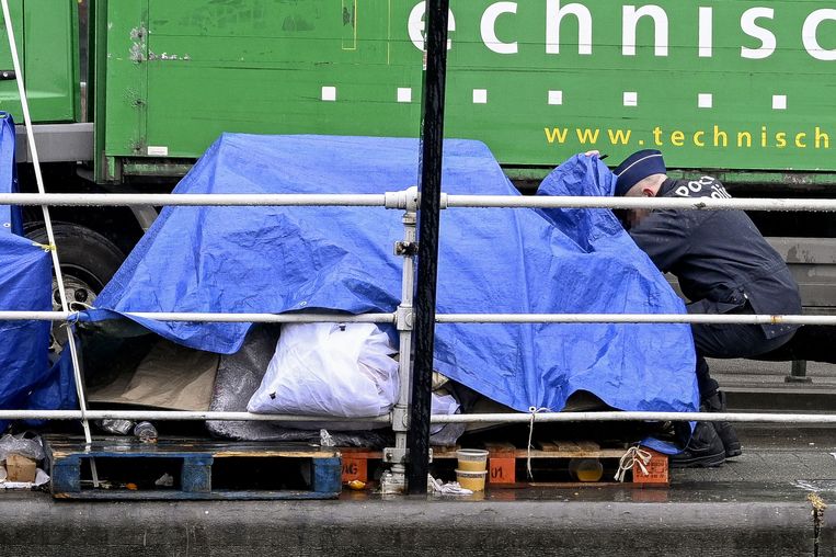 Een agent ontruimt een tent voor het Brusselse aanmeldcentrum Petit Chateau - Klein Kasteeltje Fedasil. Beeld AFP