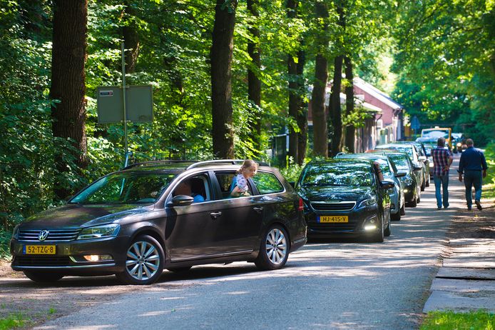 Auto’s rijden het bos in naar de Apenheul-parkeerplaats op de AGOVV-velden.