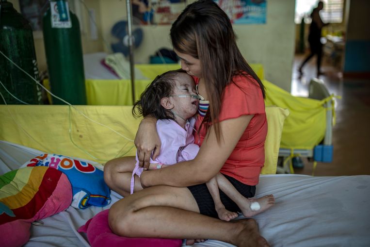Een Filippijnse moeder houdt haar dochtertje vast dat met mazelen in een ziekenhuis in Manila is opgenomen. Beeld Getty Images