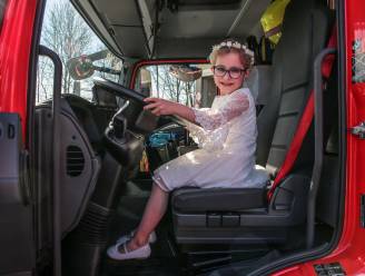 Communicantjes blinken in hun vel achter het stuur van de brandweerwagen