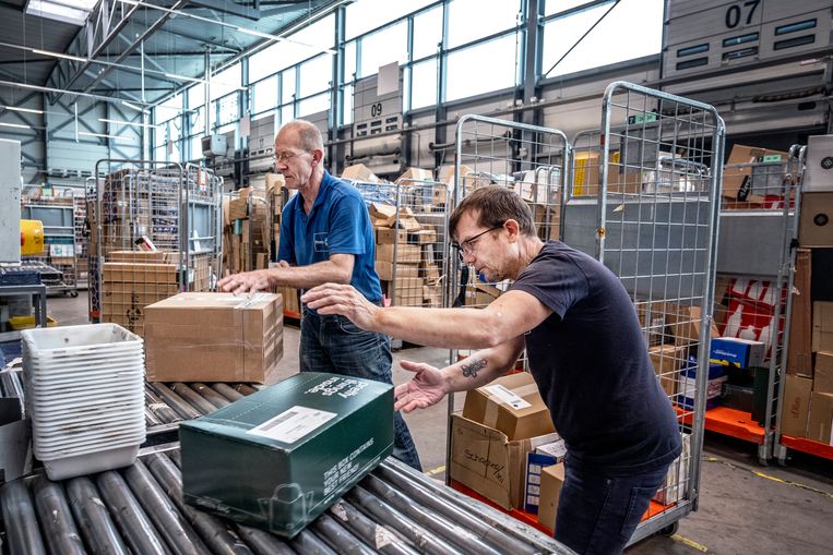Augustus 2022: medewerkers van een  sociale werkplaats werken bij de pakketdienst van PostNL in Waddinxveen. Beeld Raymond Rutting / de Volkskrant