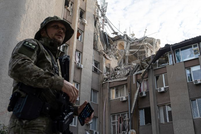 Een Oekraïense militair staat voor een gebouw dat zwaar werd beschadigd door een Russische luchtaanval in Cherson.