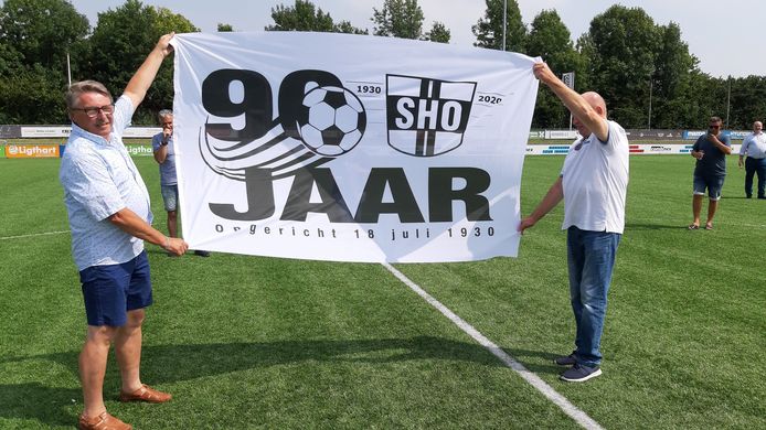 SHO-voorzitter Bas Verbaas toont samen met Adrie Troeleman (links) de jubileumvlag die de preses heeft gekregen.