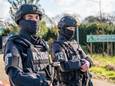 Zwaarbewapende politiemannen bewaken het terrein aan de Heitrak in Neerkant waar de politie in februari 2021 een drugslab vond.