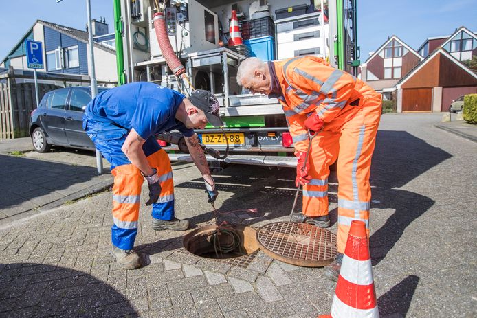 Twee medewerkers van de gemeente inspecteren een riool in De Leyens.