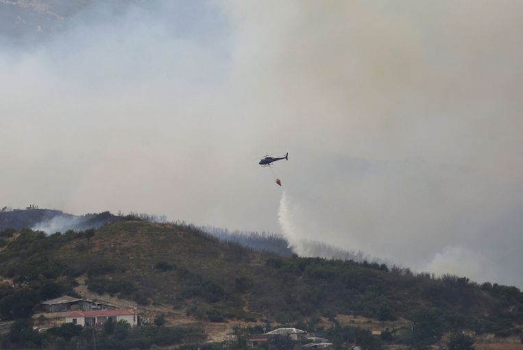 Een blushelikopter gooit water over het dorp Gjorm, vlakbij de stad Vlora in Albanië. Beeld AFP