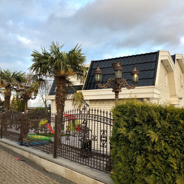 Kunststof villa met palmbomen en gesloten rolluiken op een vakantiepark. Beeld 