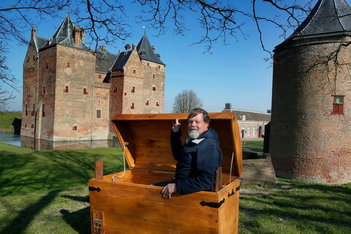 Beheerder Jacques Mombers in de boekenkist voor Slot Loevestein. Naast hem staat de kruittoren.