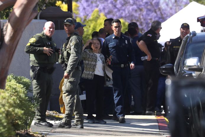 Een vrouw praat met politieagenten aan de kerk waar de schietpartij plaatsvond.