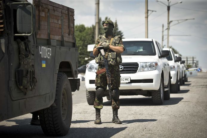 Archiefbeeld: een soldaat staat bij een controlepost in Oekraïne voor drie auto's van de OVSE .