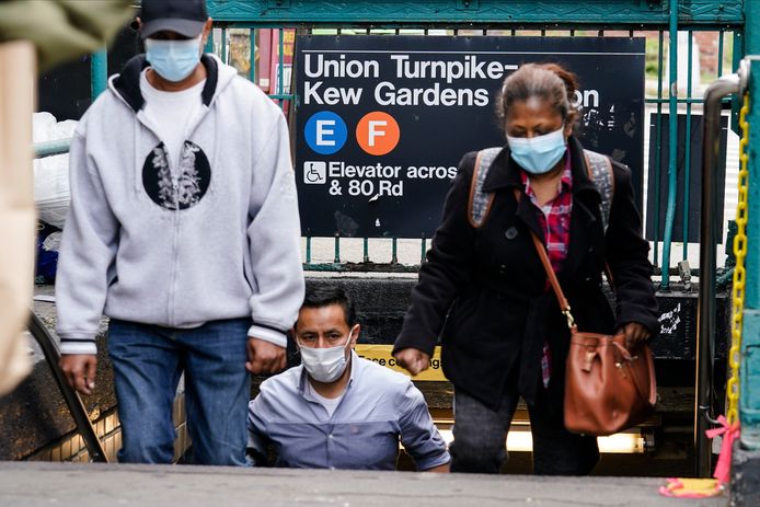 Mensen met mondmaskers op komen uit het metrostation Kew Gardens in Queens, New York.