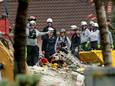 Reddingswerkers tussen het puin van het ingestorte gebouw.