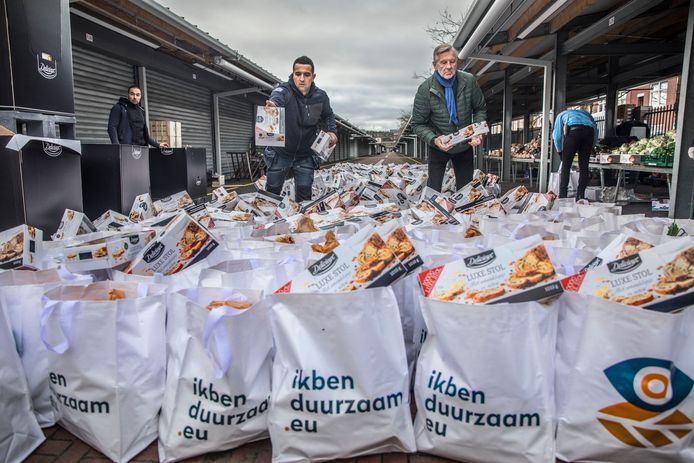 Aad van Loenen en Appie vullen samen met jongeren tasjes met voedsel om uit te delen.