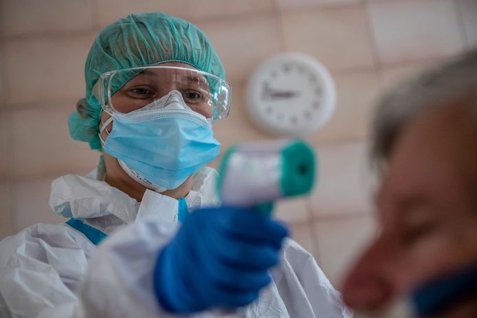 Een hulpverlener neemt de koorts van een patiënt in een ziekenhuis in Praag.