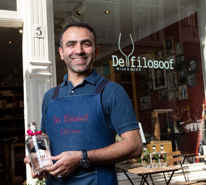 Ofran Badakh­shani met een fles vodka van het merk Rumi voor zijn winkel De Filosoof in de Papestraat.