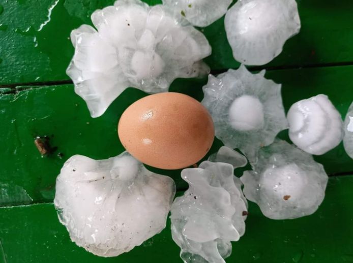 Su un tavolo accanto a un uovo, ci sono diverse palline di grandine di forme diverse.