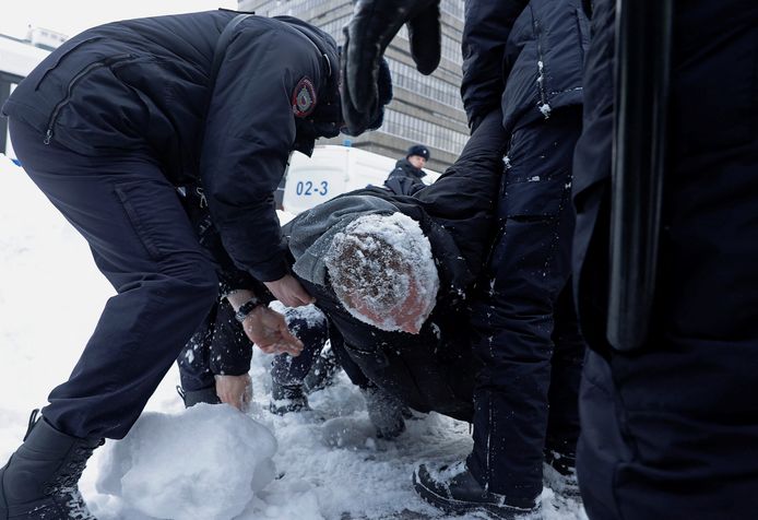 Agenten pakken een man op bij het herdenkingsmonument waar mensen samen komen voor Navalny.