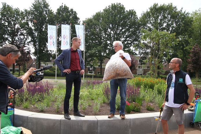 Harry Welp, voorzitter van Stichting GoClean Veldhoven, overhandigt de zak met peuken aan wethouder Jeroen Rooijakkers.