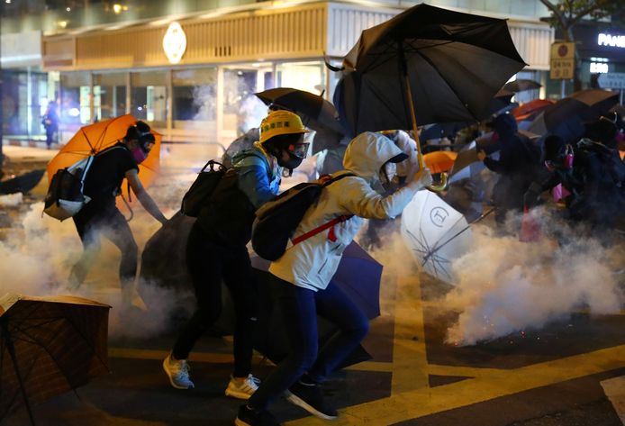 Demonstranten rennen in een wolk van traangas weg van de politie.