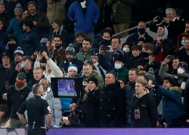 Scheidsrechter Paul Tierney bekijkt een spelherhaling tijdens Tottenham-Liverpool, terwijl de fans (vaak zonder mondmasker) in de tribunes staan. Beeld Action Images via Reuters