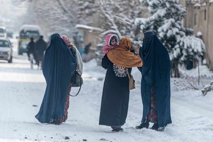 Vrouwen wandelen met hun kinderen door de besneeuwde straten van Kaboel.