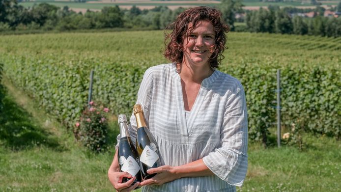 Nele Callens, medewerkster op het wijndomein Entre-Deux-Monts tussen de druivenranken, met twee wijnen in de hand die onlangs in de prijzen vielen.