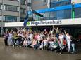 Het blije personeel van de afdeling verloskunde poseert met gebak voor de ingang van het Zoetermeerse ziekenhuis.