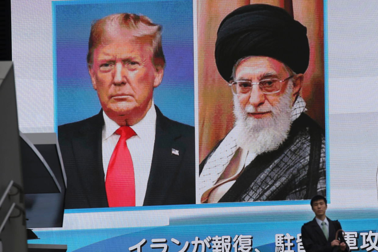 Een man in Japan loopt langs een billboard met daarop het laatste nieuws over de spanningen tussen de VS en Iran. De hoogste leider van Iran, Ali Khamenei, en de Amerikaanse president Donald Trump staan lijnrecht tegenover elkaar.  Beeld AP